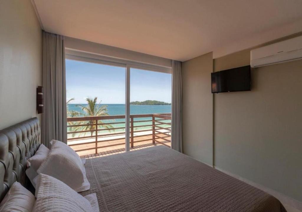 a bedroom with a bed with a view of the ocean at Pousada Castellammare in Bombinhas