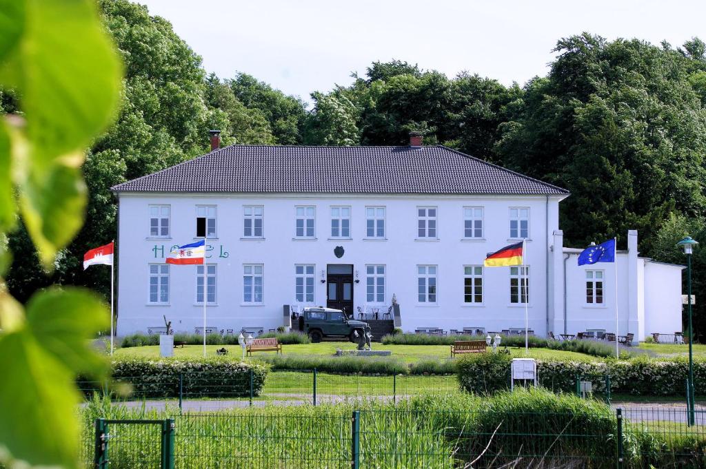 un gran edificio blanco con banderas delante en Ostsee-Gutshaus Am Salzhaff Pepelow nähe Rerik- am Meer residieren!, en Klein Strömkendorf