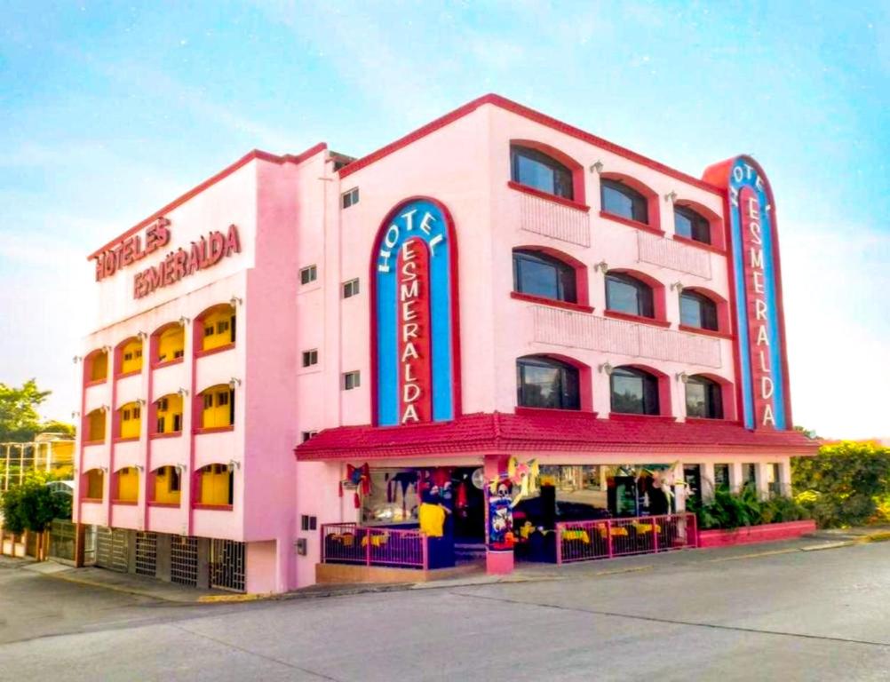 a pink building with a restaurant in front of it at Hotel Esmeralda in Poza Rica de Hidalgo
