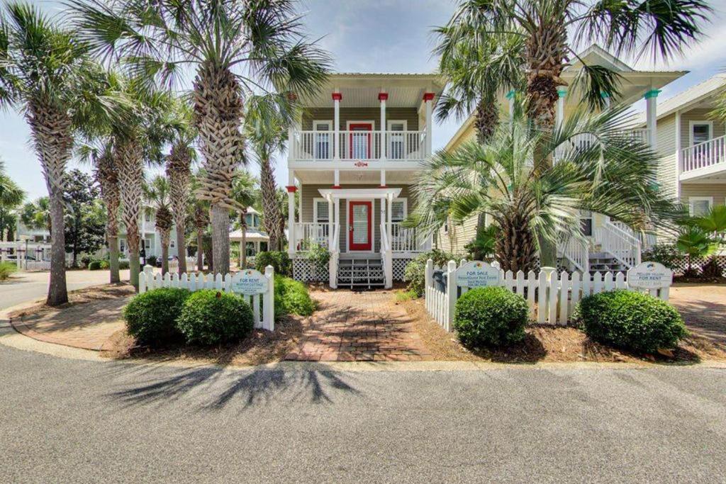 a white fence in front of a house with palm trees at Redfish Cottage in Santa Rosa Beach