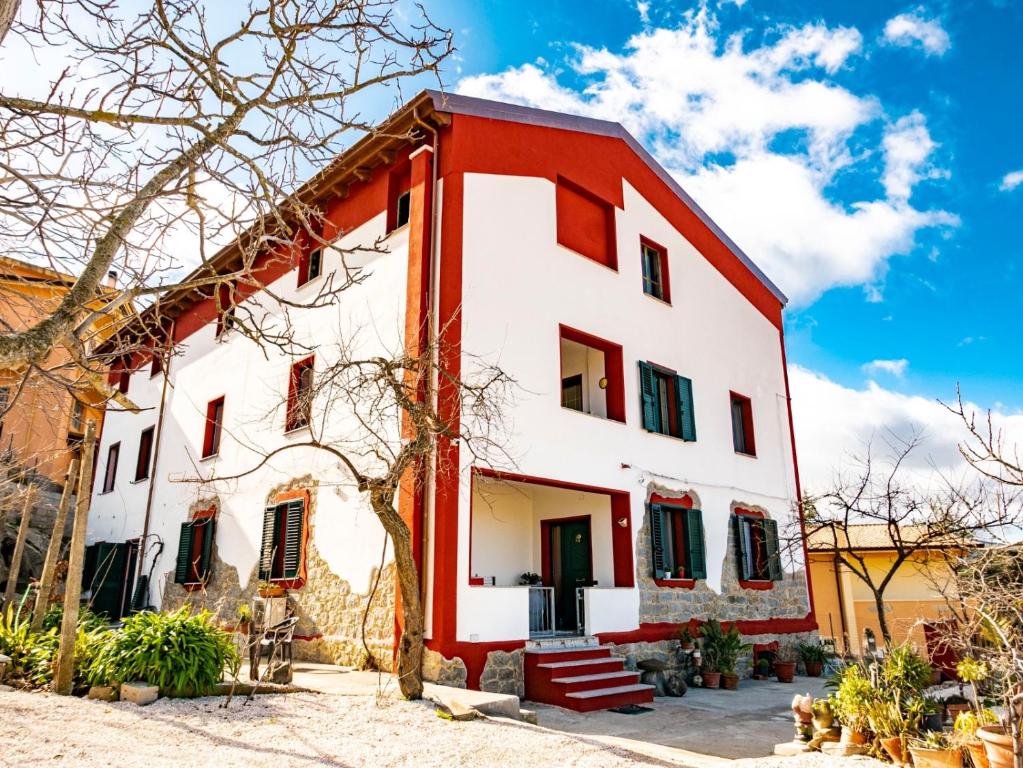 uma casa vermelha e branca com persianas verdes em le Rose di santina em Mamoiada