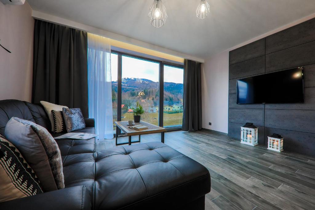 un soggiorno con divano e una grande finestra di Apartament Marron a Szczyrk