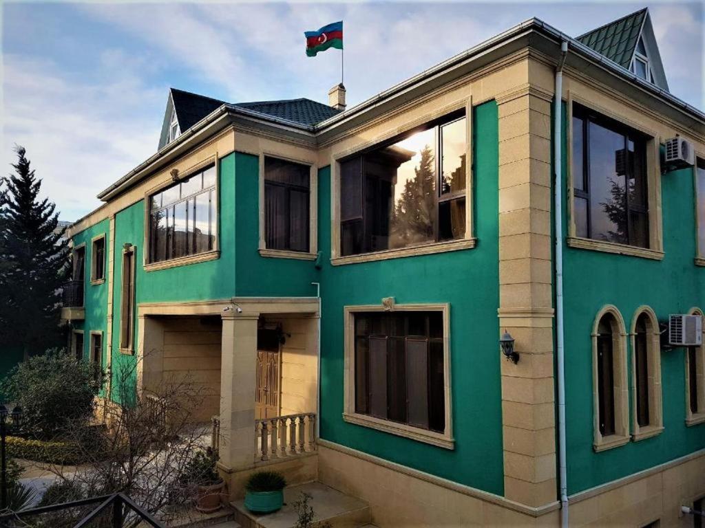 巴庫的住宿－Ansera Badamdar，一座绿色房子,上面有旗帜