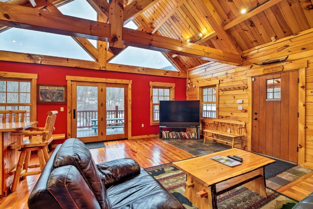 a living room with a couch and a table and a tv at Ski Lodge Mtn Retreat with Fire Pit, Deck and Views! in Starksboro