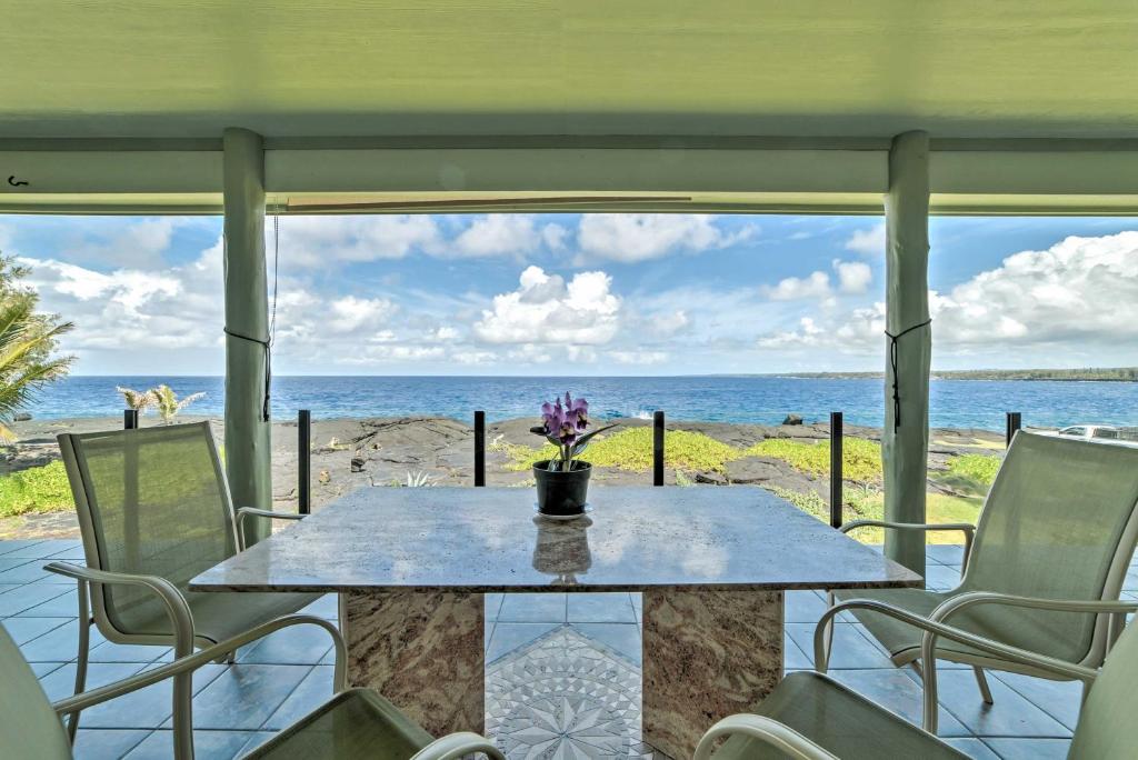 a table with chairs and a view of the ocean at Direct Oceanfront, Big Island Vacation Rental Home in Keaau