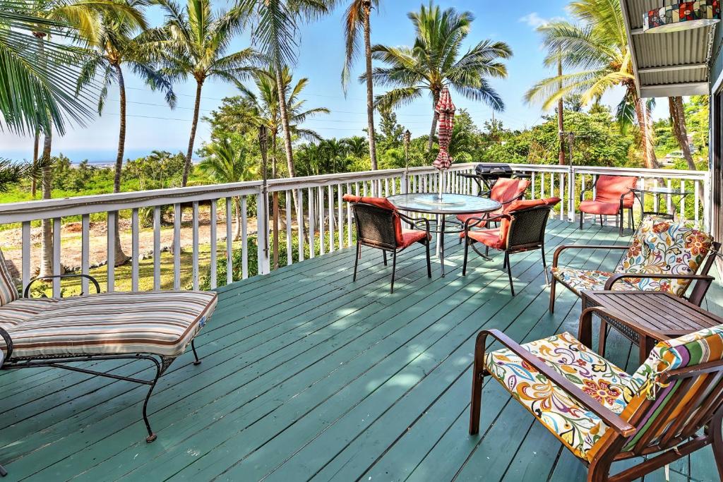 a deck with chairs and tables and palm trees at Breezy Kailua-Kona Bungalow with Lanai and Ocean View! in Kailua-Kona