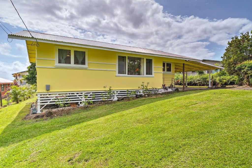 a yellow house with a lawn in front of it at Charming Historic Hilo House Minutes to Beach! in Hilo