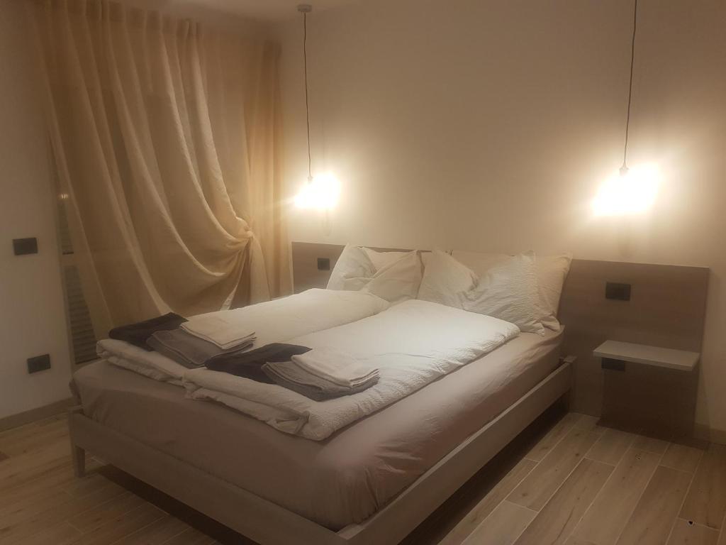 uma cama branca com duas luzes em cima em Alloggio Casa Talvena XL em Longarone