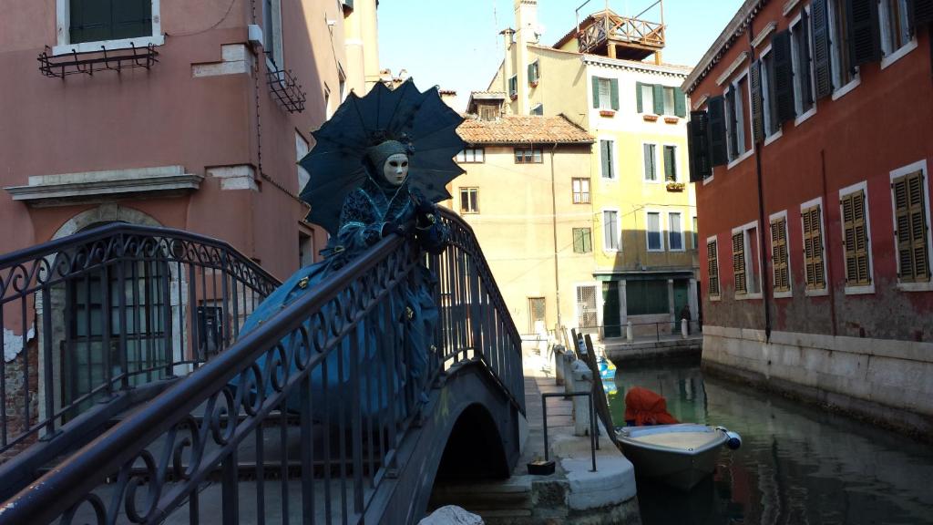 Casa Vacanze "Al Castello" Venezia في البندقية: تمثال لامرأة بمظلة على جسر