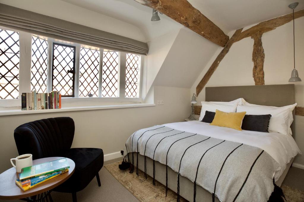 a bedroom with a bed and a chair and windows at Cotswolds Place - Chancewell in Broadway