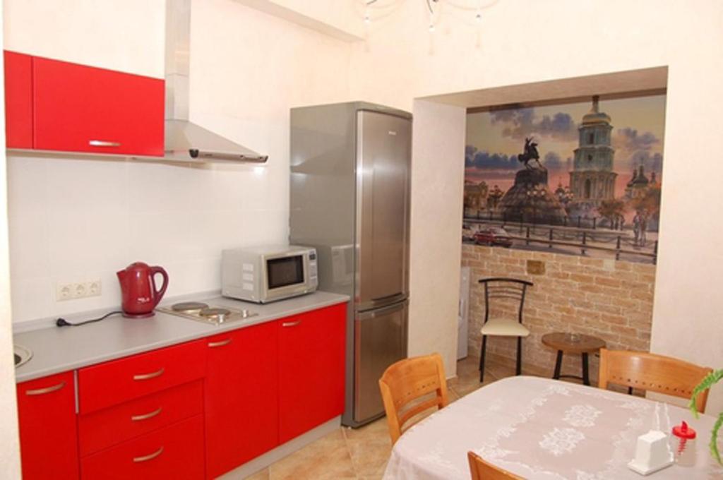 eine Küche mit roten Schränken und einem Tisch mit einer Mikrowelle in der Unterkunft Sofiivs'ka Street, 1,, in Kiew