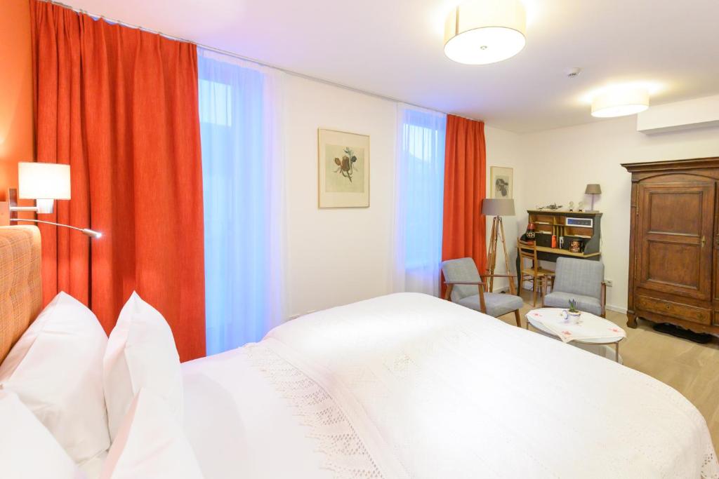 a bedroom with a white bed and red curtains at Berdorfer Eck - Bed&Breakfast in Berdorf