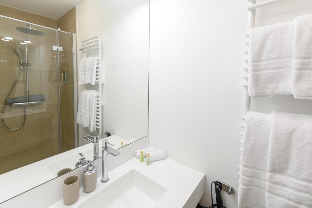 a white bathroom with a sink and a shower at Berdorfer Eck - Bed&Breakfast in Berdorf