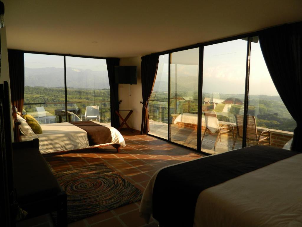 Cette chambre comprend deux lits et une grande fenêtre en verre. dans l'établissement Sierra Morena Eco Hotel, à Filandia