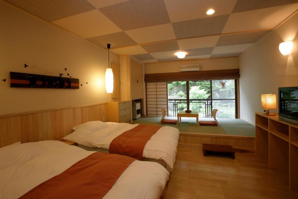 小諸市にある菱野温泉 常盤館のベッド2台とテレビが備わるホテルルームです。