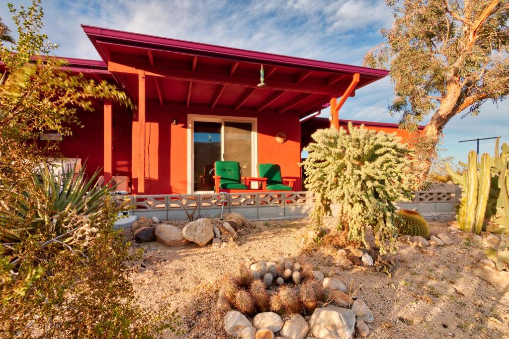 a red house with green chairs in front of it at Chuck's Cabin in a Joshua Tree Community in Twentynine Palms