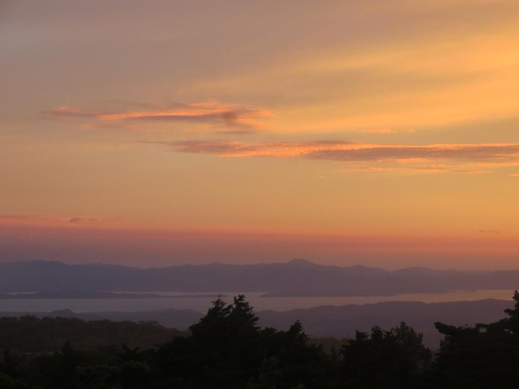 una puesta de sol sobre el agua con árboles en el primer plano en Apartamento ArteSAna, en Monteverde