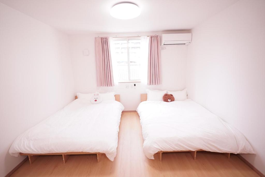 2 camas en una habitación con ventana en 暁 Twilight Osaka Inn en Osaka