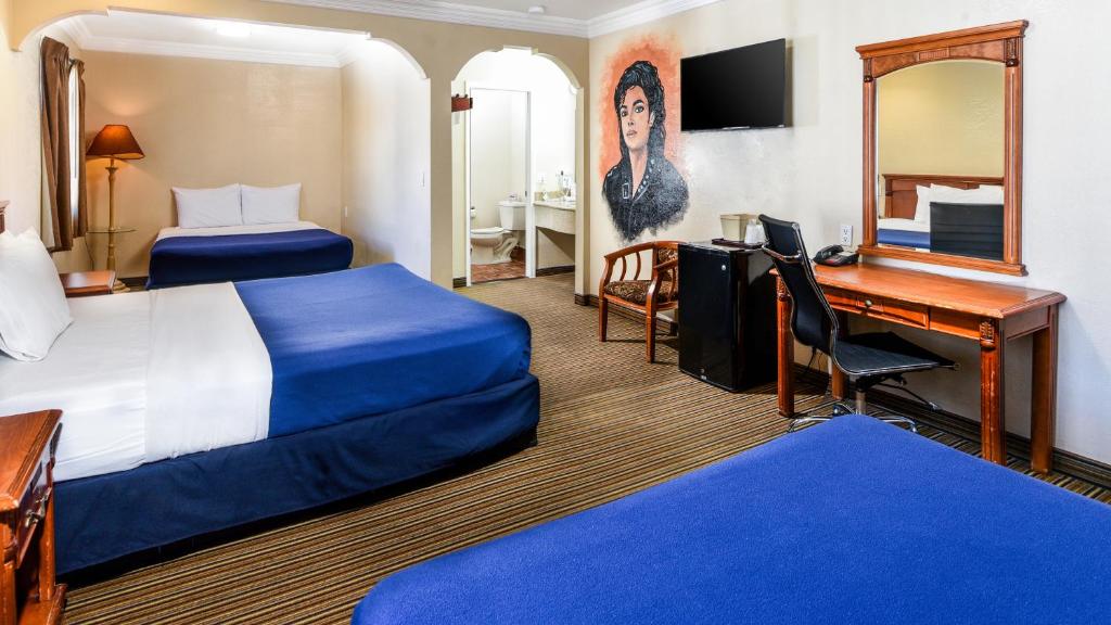 a hotel room with two beds and a desk at Hollywood Inn Express North in Los Angeles