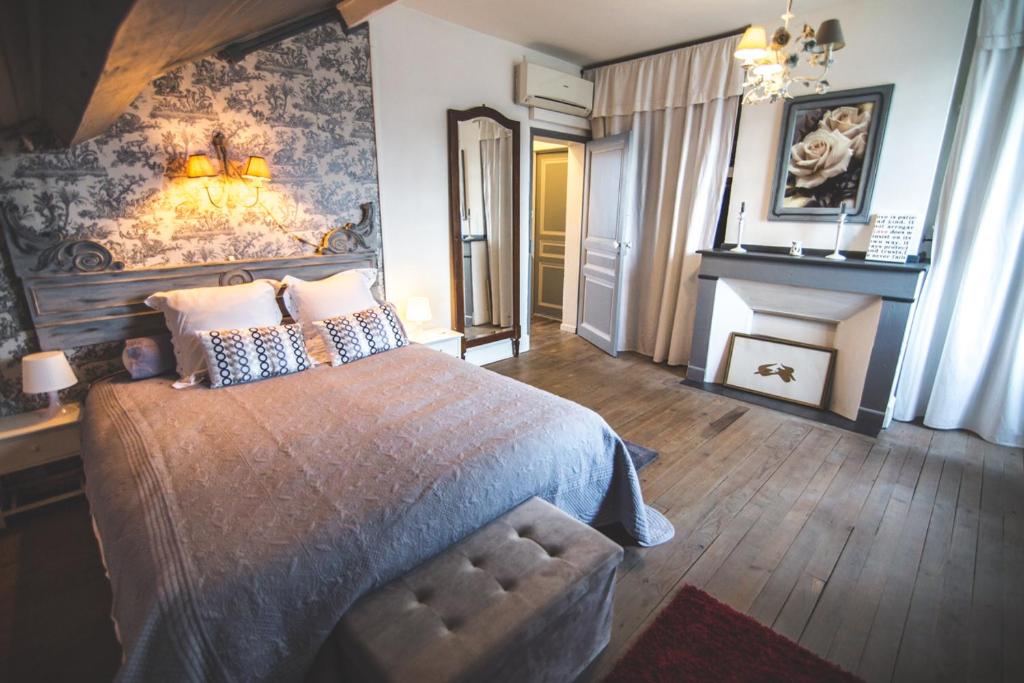 a bedroom with a large bed and a fireplace at Au Bien Venu in Noé