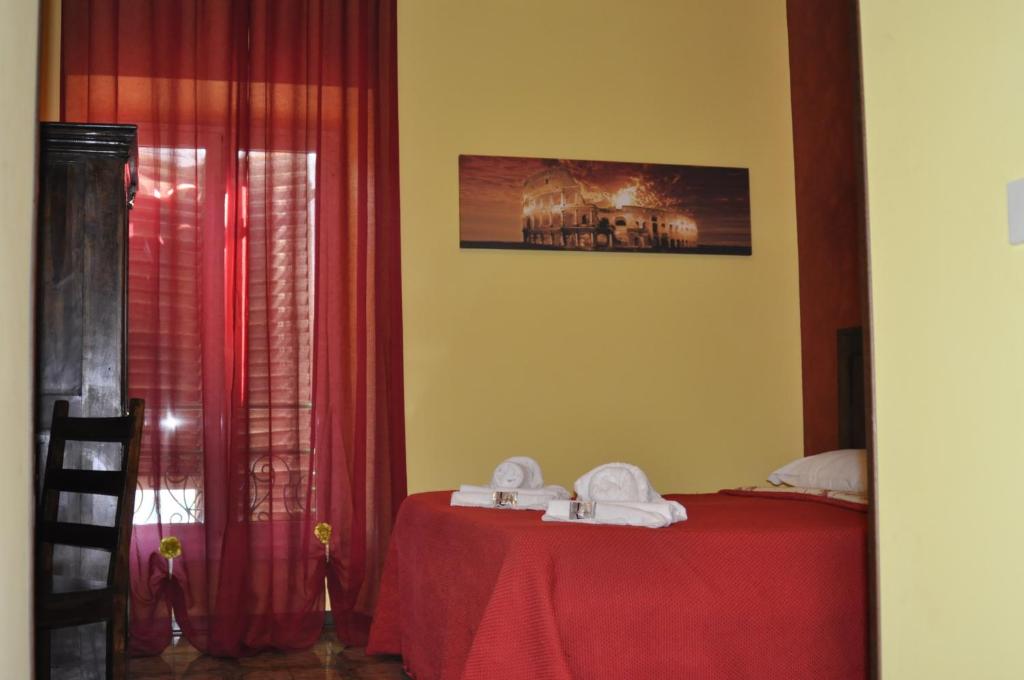 a bedroom with a bed with red curtains and a table at Amico Hotel in Rome