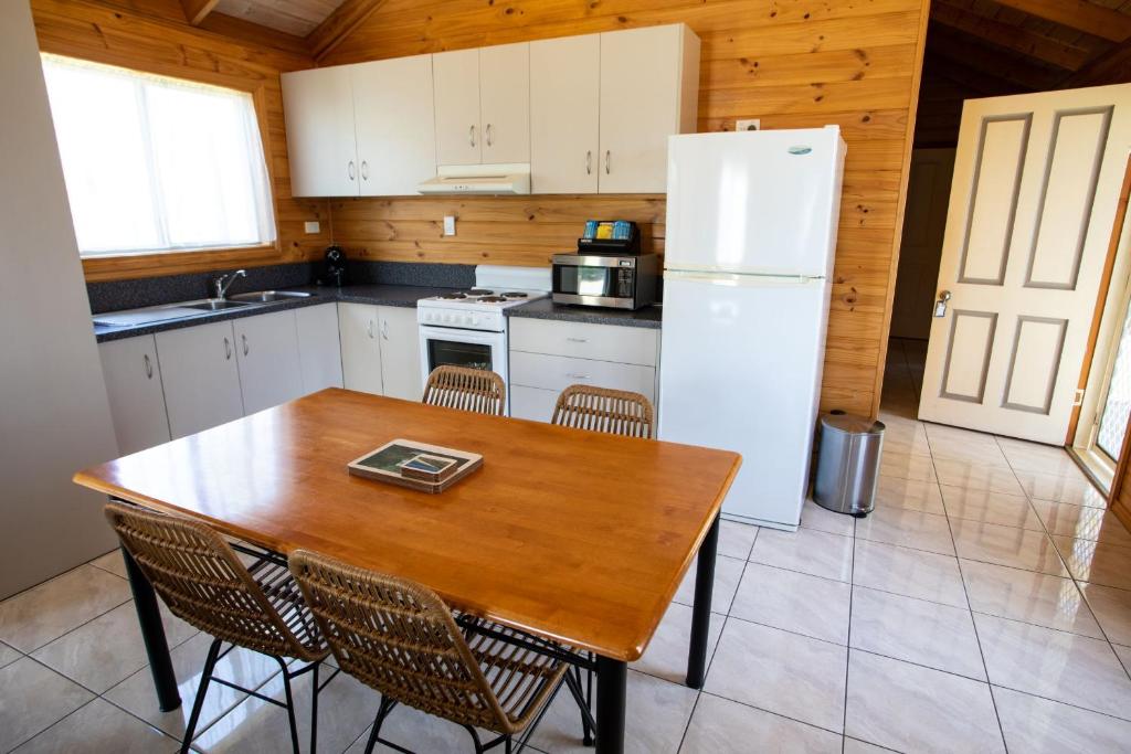 a kitchen with a wooden table and a white refrigerator at Beauty Point Tourist Park in Beauty Point