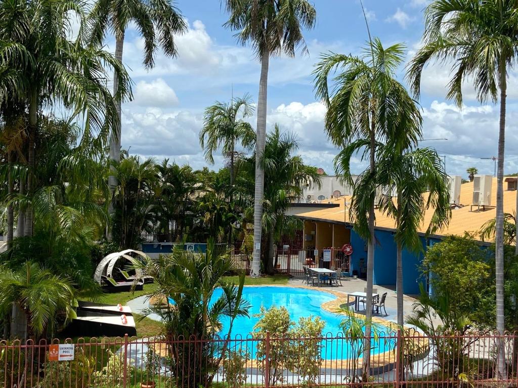 a pool at a resort with palm trees at Katherine Motel in Katherine