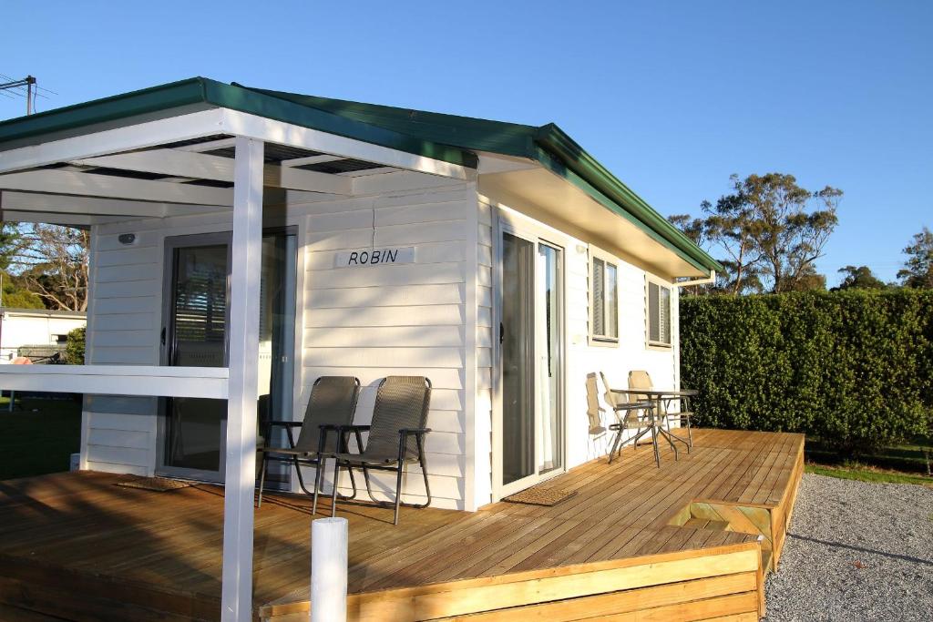 a white tiny house with chairs and a deck at Beauty Point Tourist Park in Beauty Point