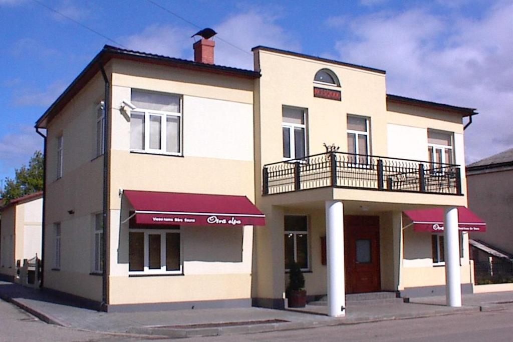 a large white building with a balcony on a street at Otrā Elpa in Valka
