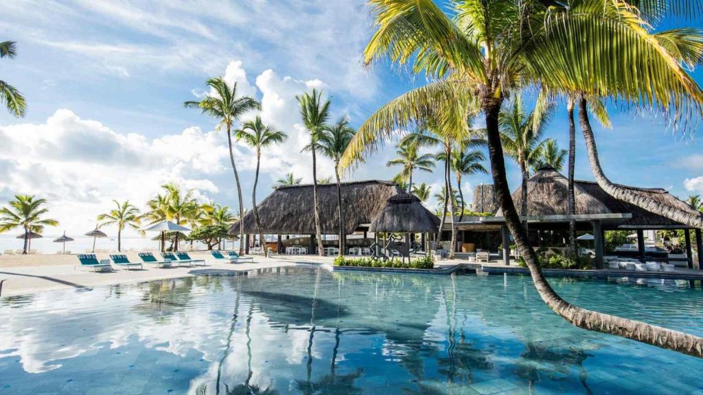 ein Pool mit Palmen und ein Resort in der Unterkunft Long Beach Mauritius in Belle Mare