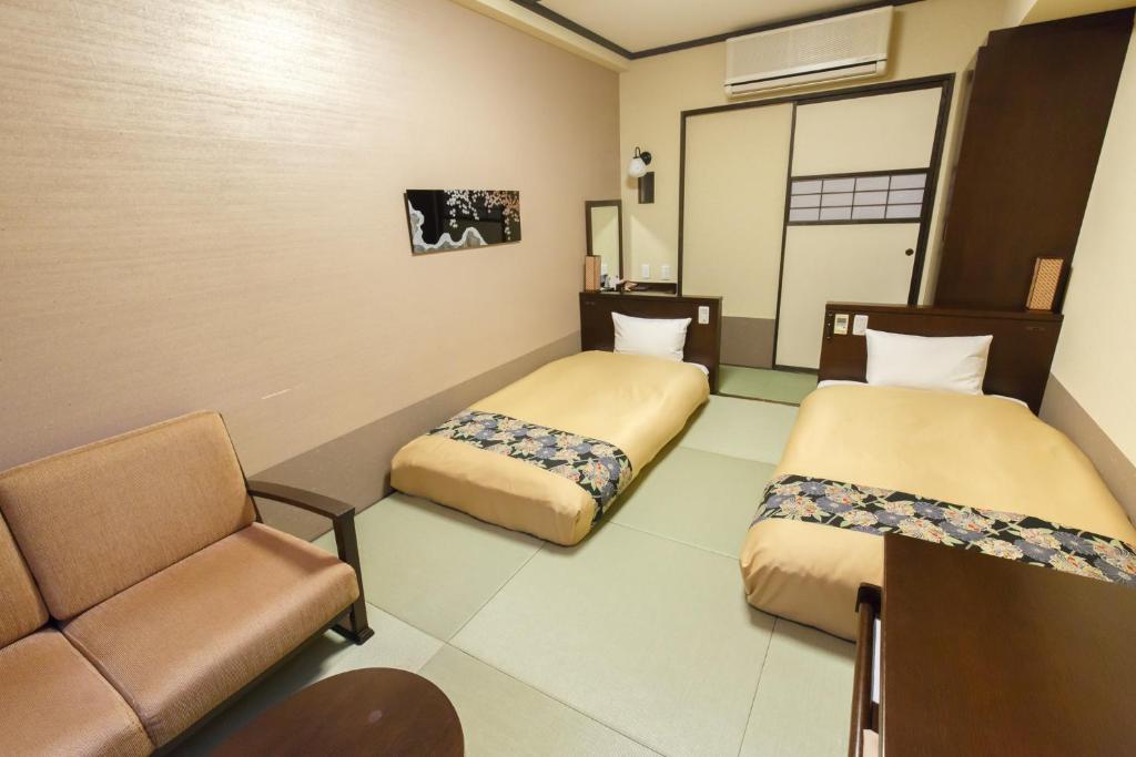 a room with two beds and a chair in it at Takayama Ouan in Takayama