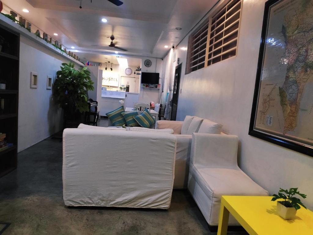a living room with white couches and a yellow table at Crossroads Hostel Manila in Manila