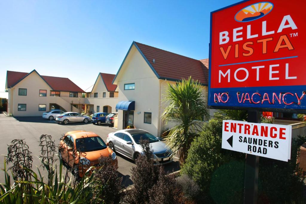 um sinal para um motel com carros estacionados num parque de estacionamento em Bella Vista Motel Ashburton em Ashburton