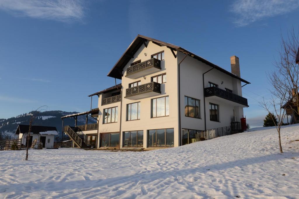 una casa en la cima de una colina nevada en PENSIUNEA ARINAS en Vatra Dornei