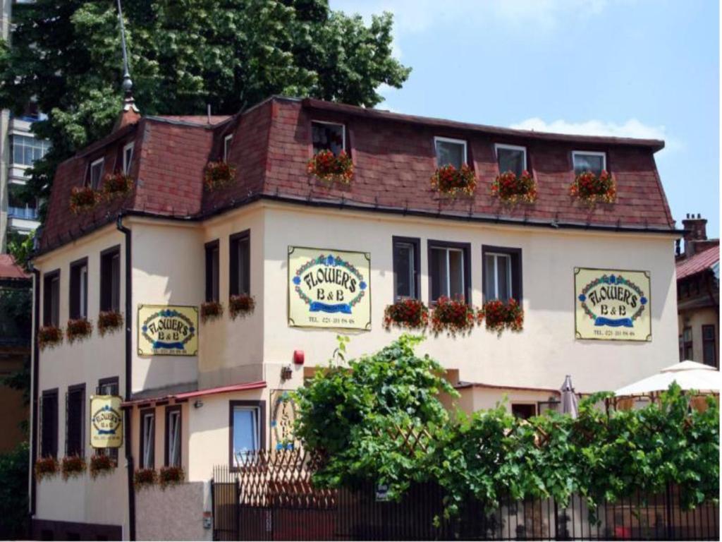 a large white building with a fence in front of it at Flower's in Bucharest