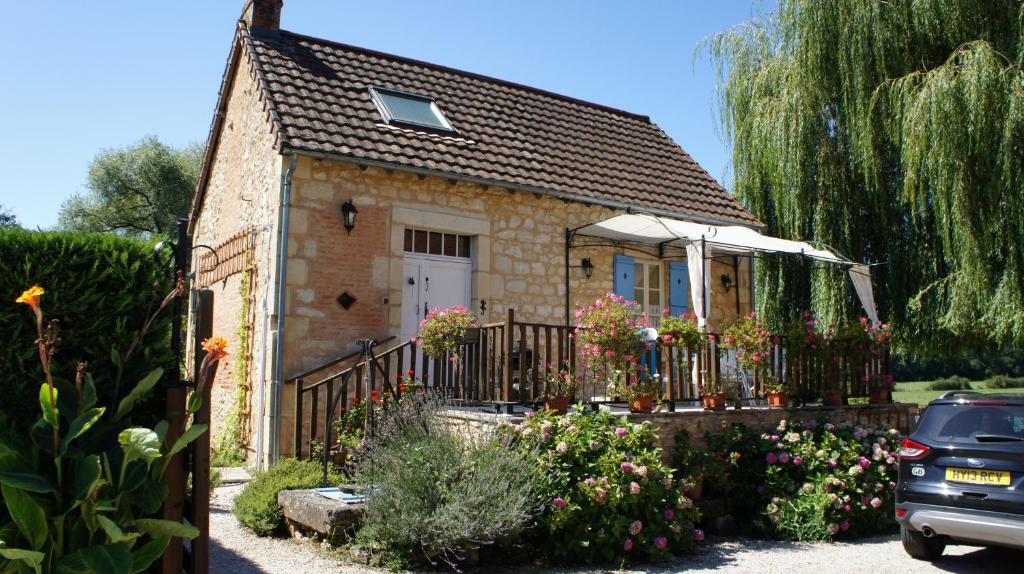 een klein huis met een hek en bloemen bij The Cottage in Hautefort