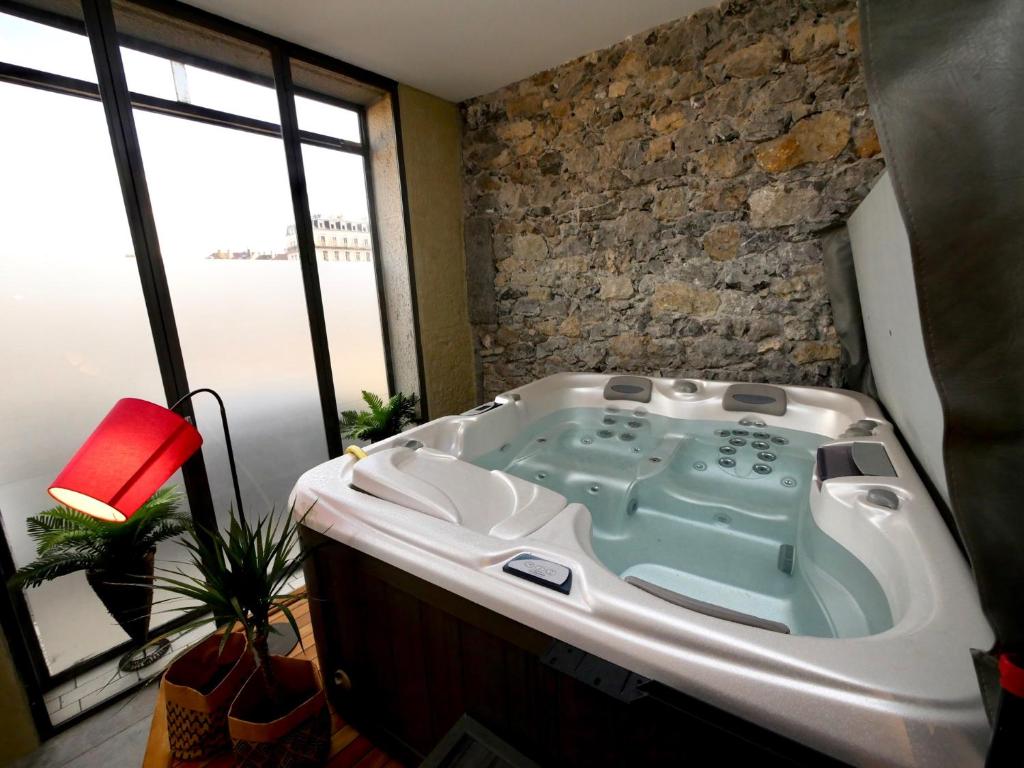 uma banheira num quarto com uma parede de pedra em Appartement spa privatif Grenoble At Home Spa em Grenoble