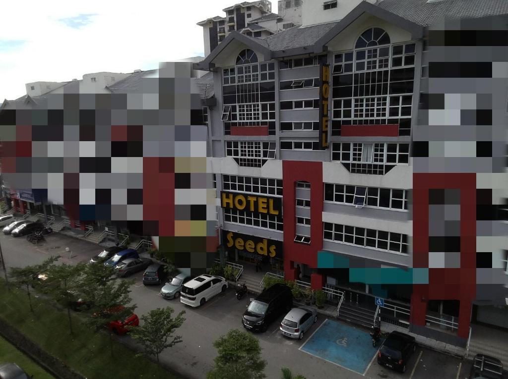 a building with a lot of cars parked in a parking lot at Seeds Hotel Ampang Point in Kuala Lumpur