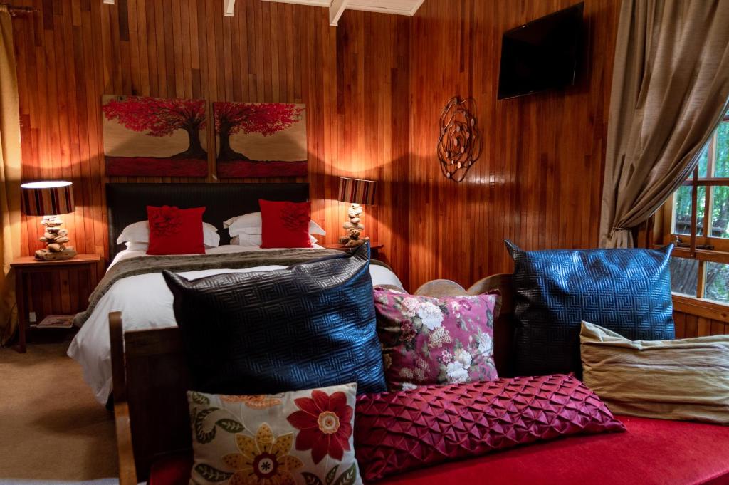 a bedroom with a bed with red and blue pillows at Ducks Country House in Henley on Klip