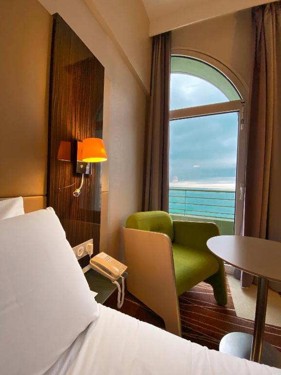 a hotel room with a bed and a chair and a window at Mercure Granville Le Grand Large in Granville