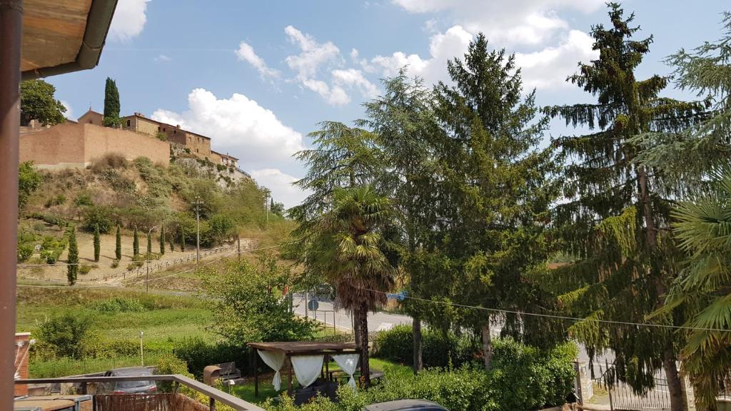 聖喬凡尼迪亞索的住宿－VAL D'ORCIA DELUXE 1 ELEGANTE CASA immersa nel verde con WiFi, giardino e parcheggio，享有树木和建筑的山丘景色