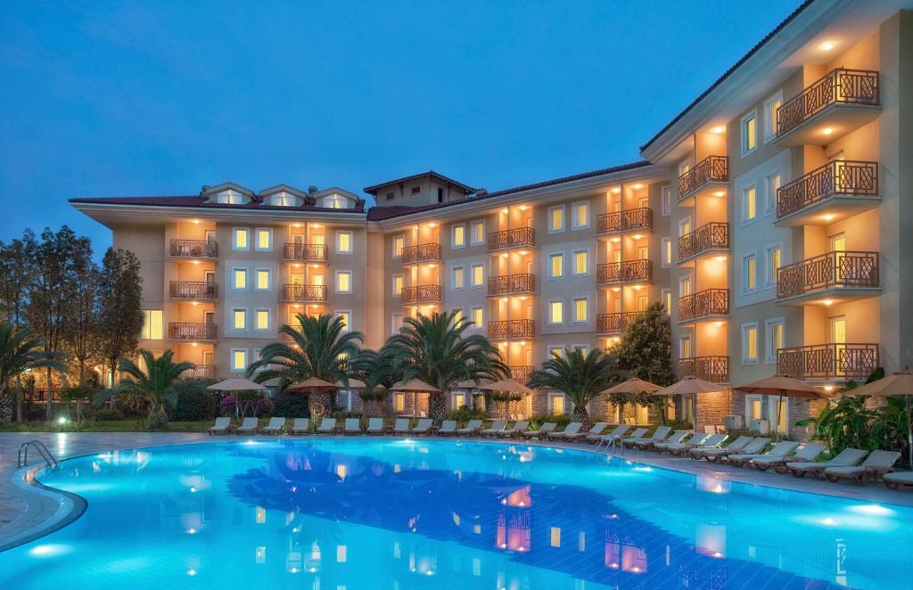 a large hotel with a large swimming pool at night at Akka Claros Hotel - All Inclusive in Kemer