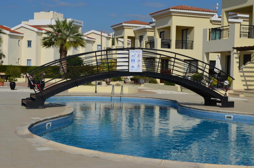 eine Brücke über einen Pool vor einigen Gebäuden in der Unterkunft Faros Beach Apartment A102 in Paphos City