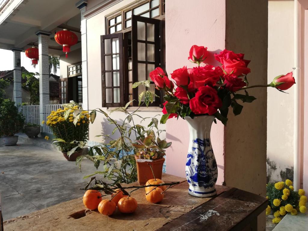 Katie's homestay في Ðông Mỹ (2): مزهرية زرقاء وبيضاء مع ورود حمراء على طاولة