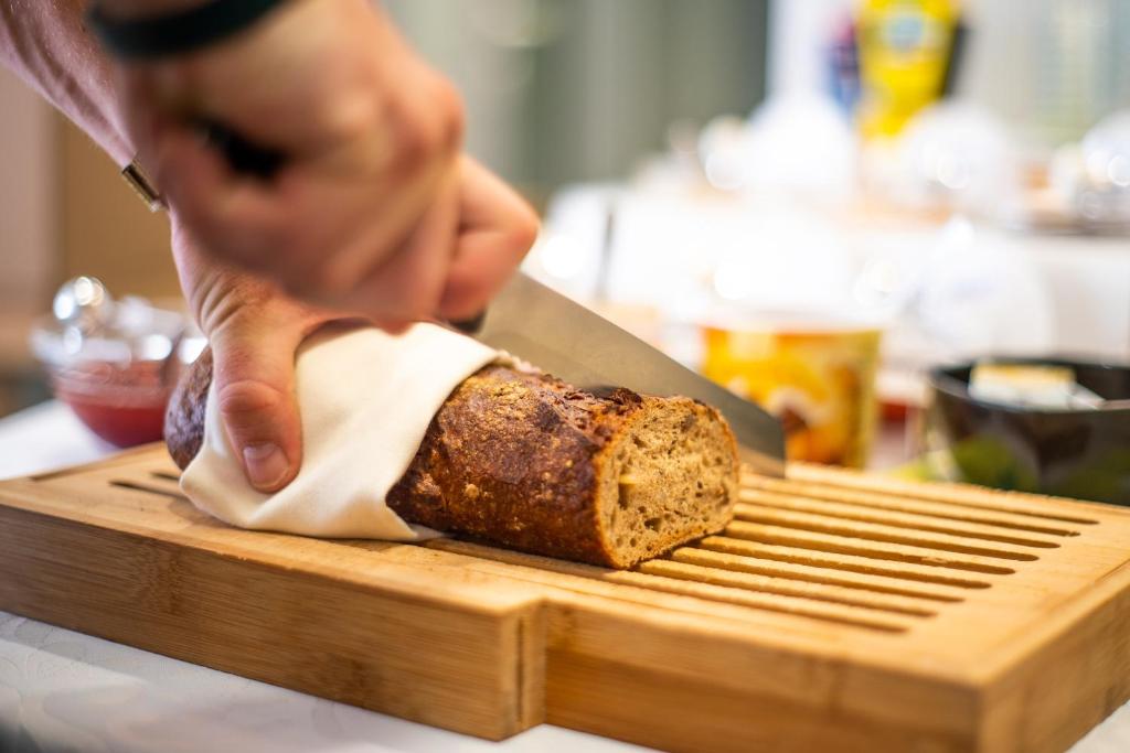 a person cutting a loaf of bread on a cutting board at Hotel Tanne in Saalfeld