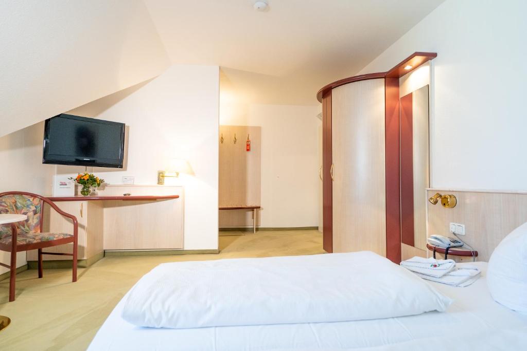 a bedroom with a white bed and a tv at Hotel Tanne in Saalfeld
