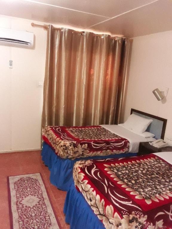 two beds in a room with a curtain at Hotel Aljazira in Nouadhibou