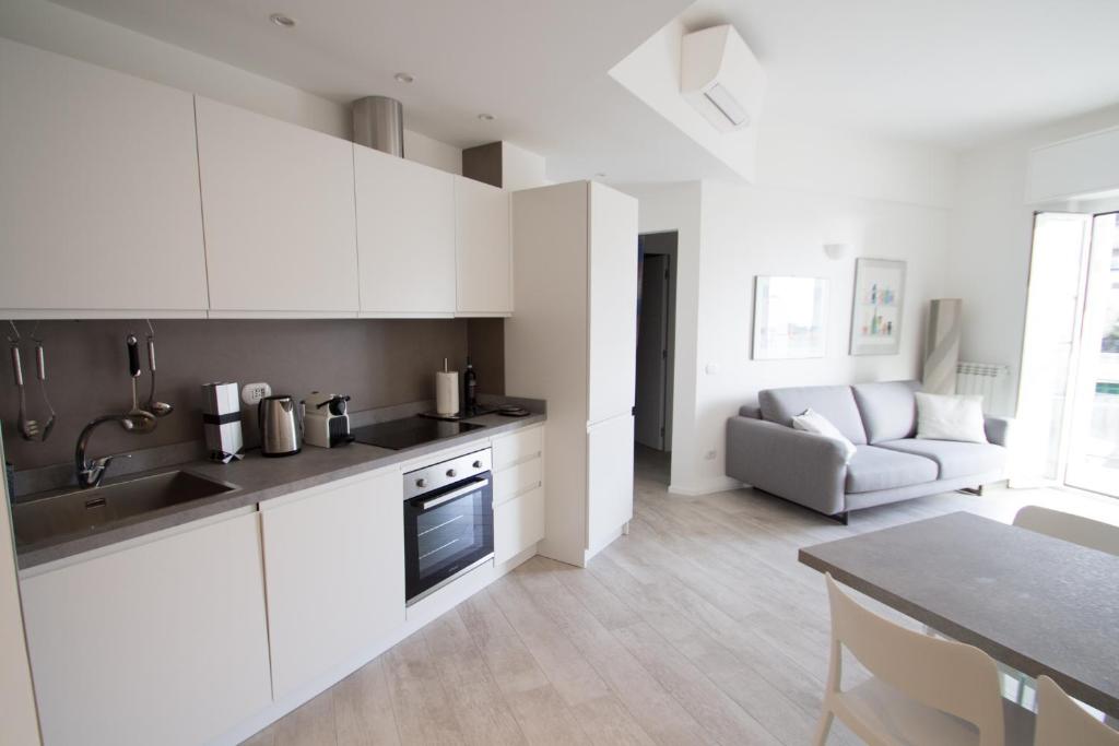 eine Küche und ein Wohnzimmer mit weißen Schränken und einem Tisch in der Unterkunft appartamento super ristrutturato in Celle Ligure