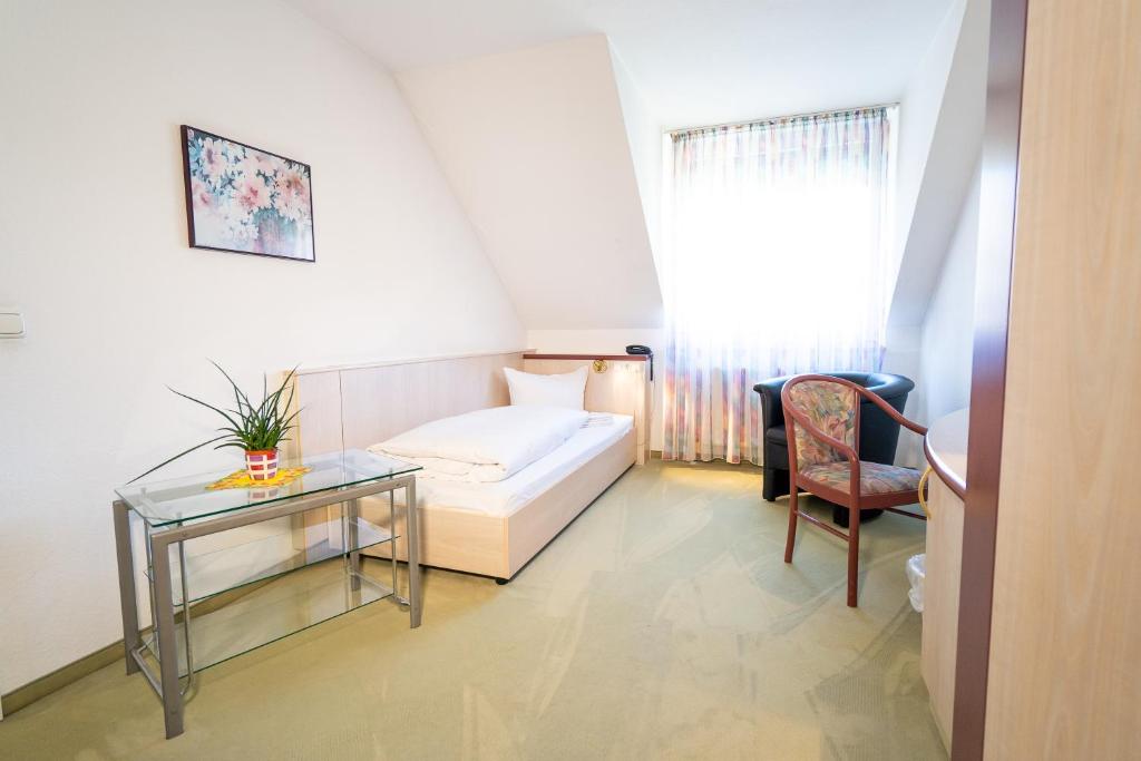 a bedroom with a bed and a table and a chair at Hotel Tanne in Saalfeld