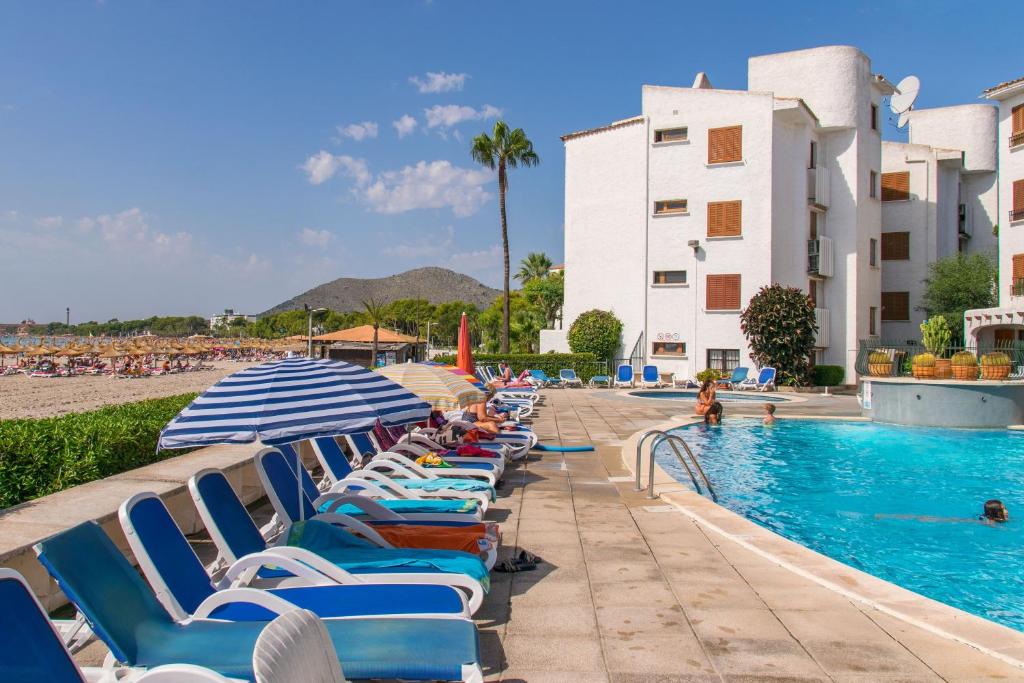 a group of chairs and umbrellas next to a swimming pool at Apartamentos Carabela CITADINI 39 in Alcudia